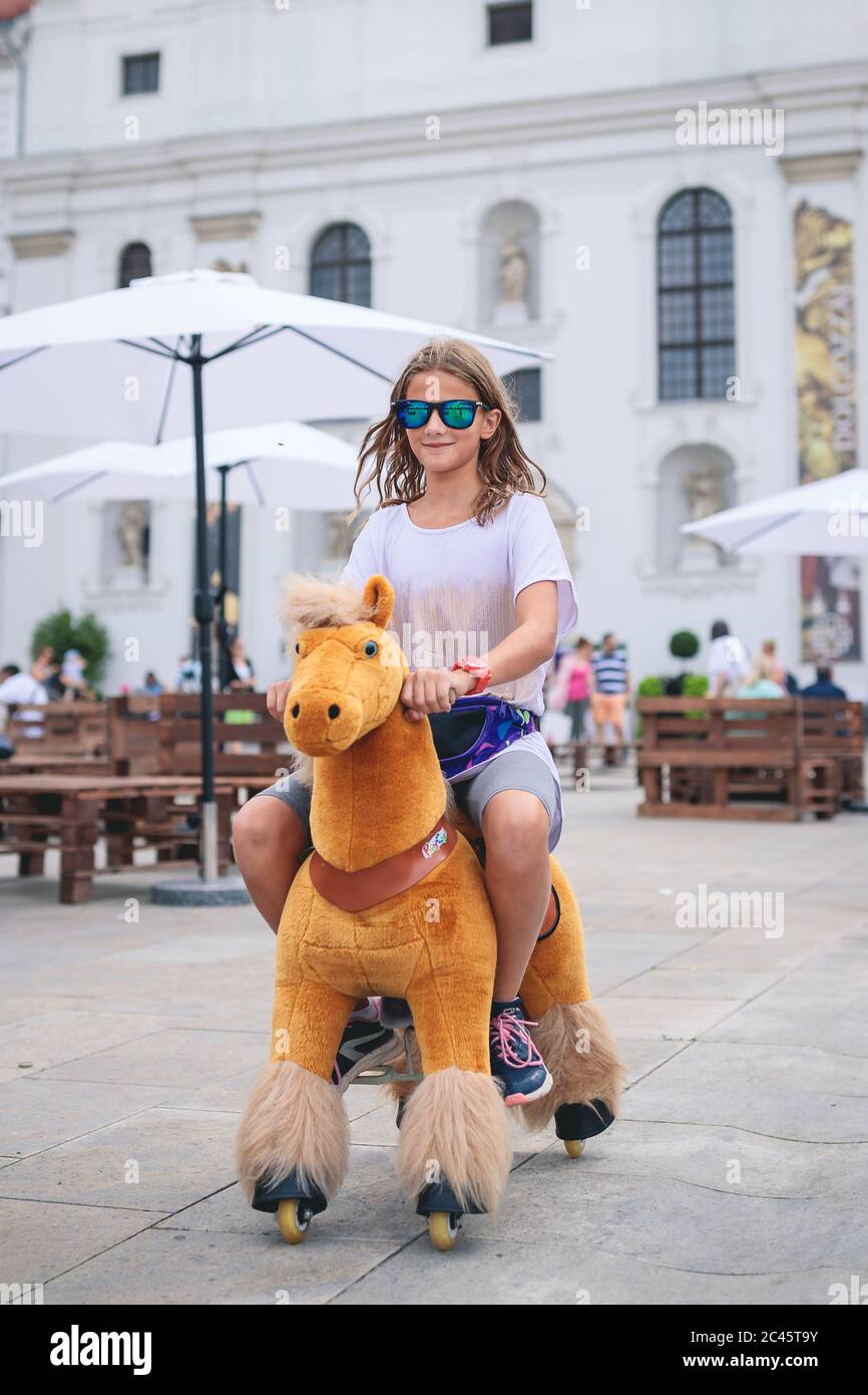 Young girl riding on old fashioned play horse at village fair Stock Photo