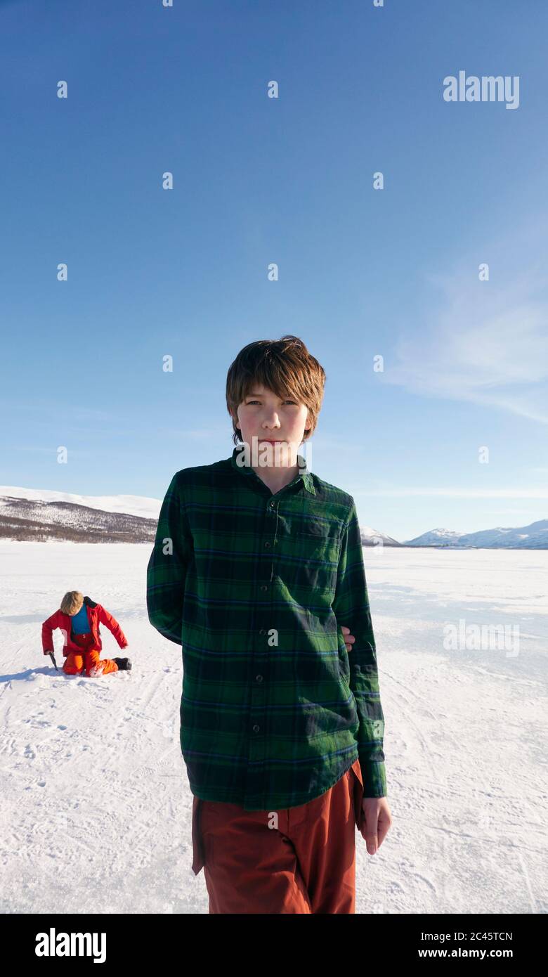 Boy standing on frozen lake in Vasterbottens Lan, Sweden, looking at camera. Stock Photo