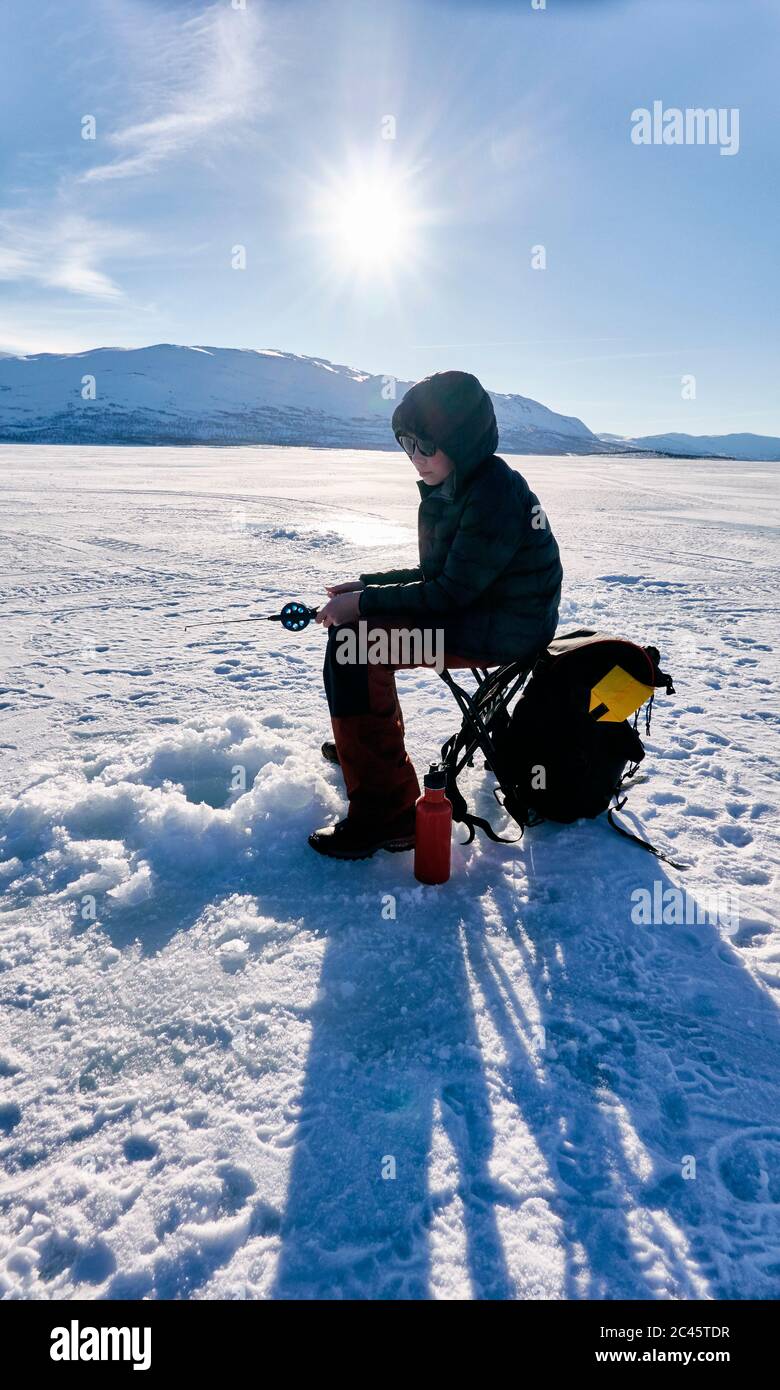 Boy ice-fishing on frozen lake in Vasterbottens Lan, Sweden. Stock Photo
