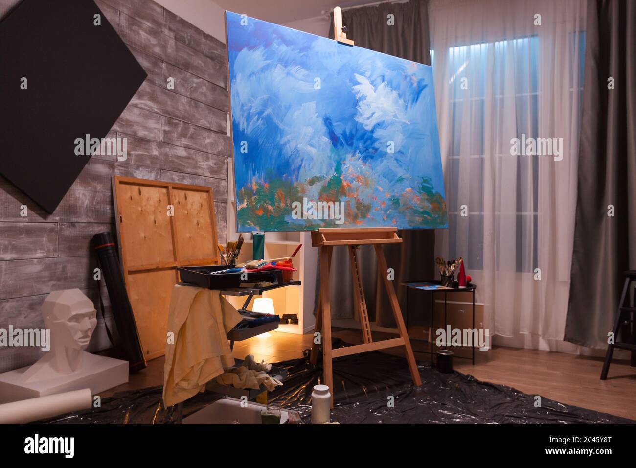 Interior of painting studio with wooden easel and blank canvas