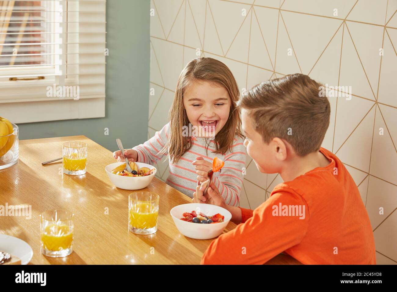 Boy and girl sitting at kitchen table, eating breakfast Stock Photo Alamy