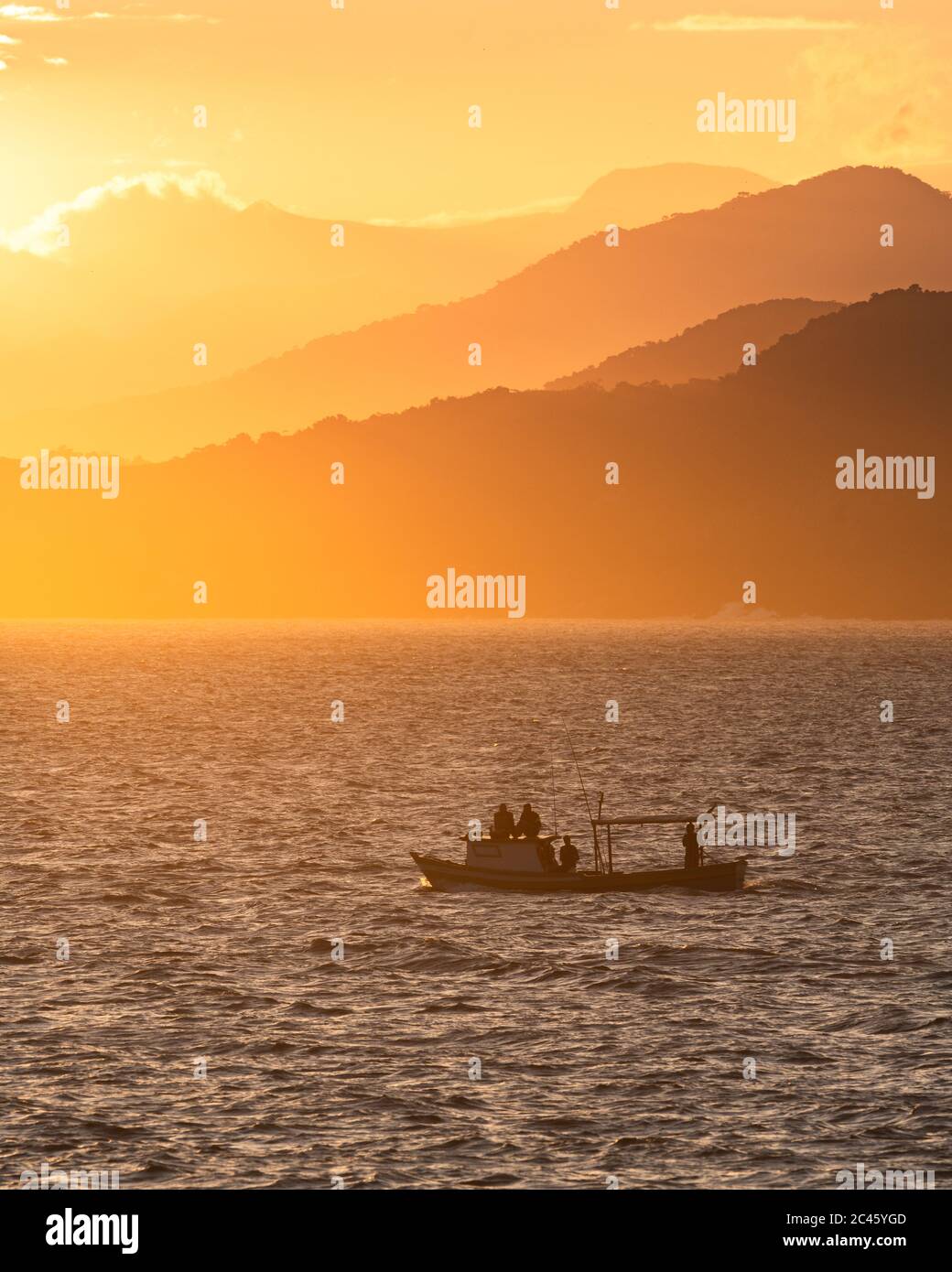 A fishing boat navigates at the southern entrance of Canal de São Sebastião, SE Brazil, during sunset Stock Photo