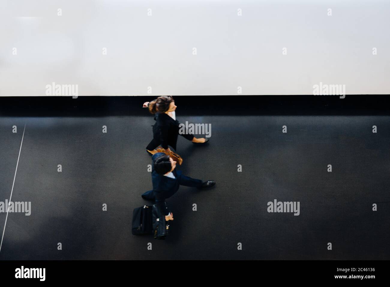 Businessman and businesswoman with wheeled luggage in hotel building Stock Photo