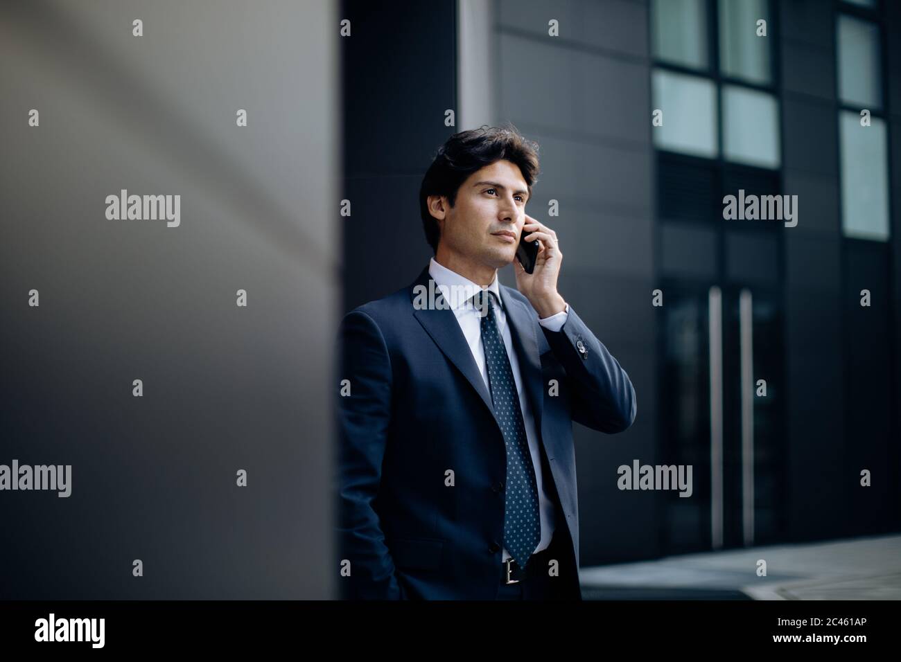 Businessman using smartphone in front of office building Stock Photo