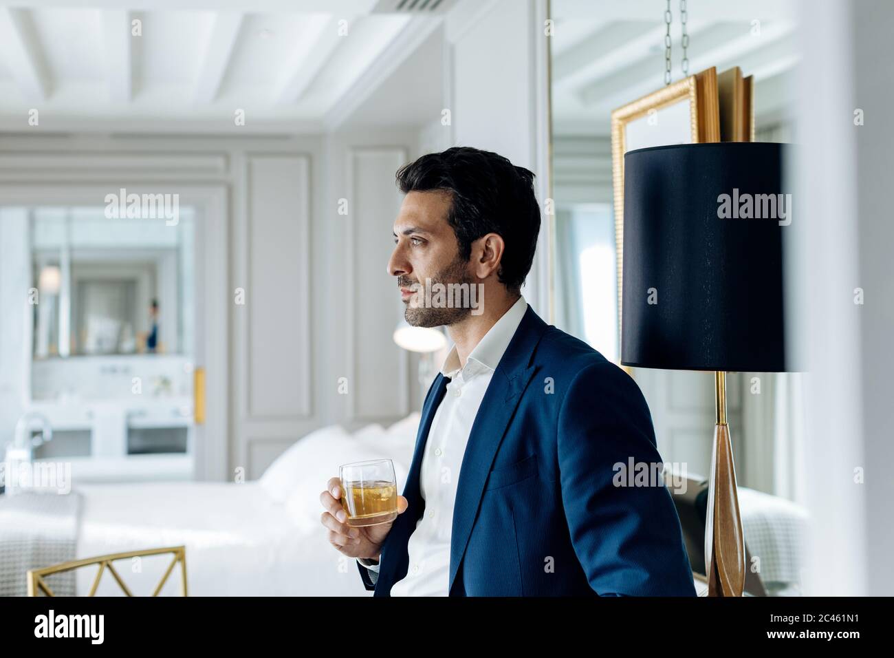 Businessman with iced drink, deep in thoughts in suite Stock Photo