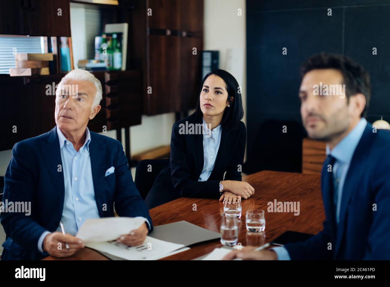 Businessmen and woman watching presentation from boardroom table Stock Photo