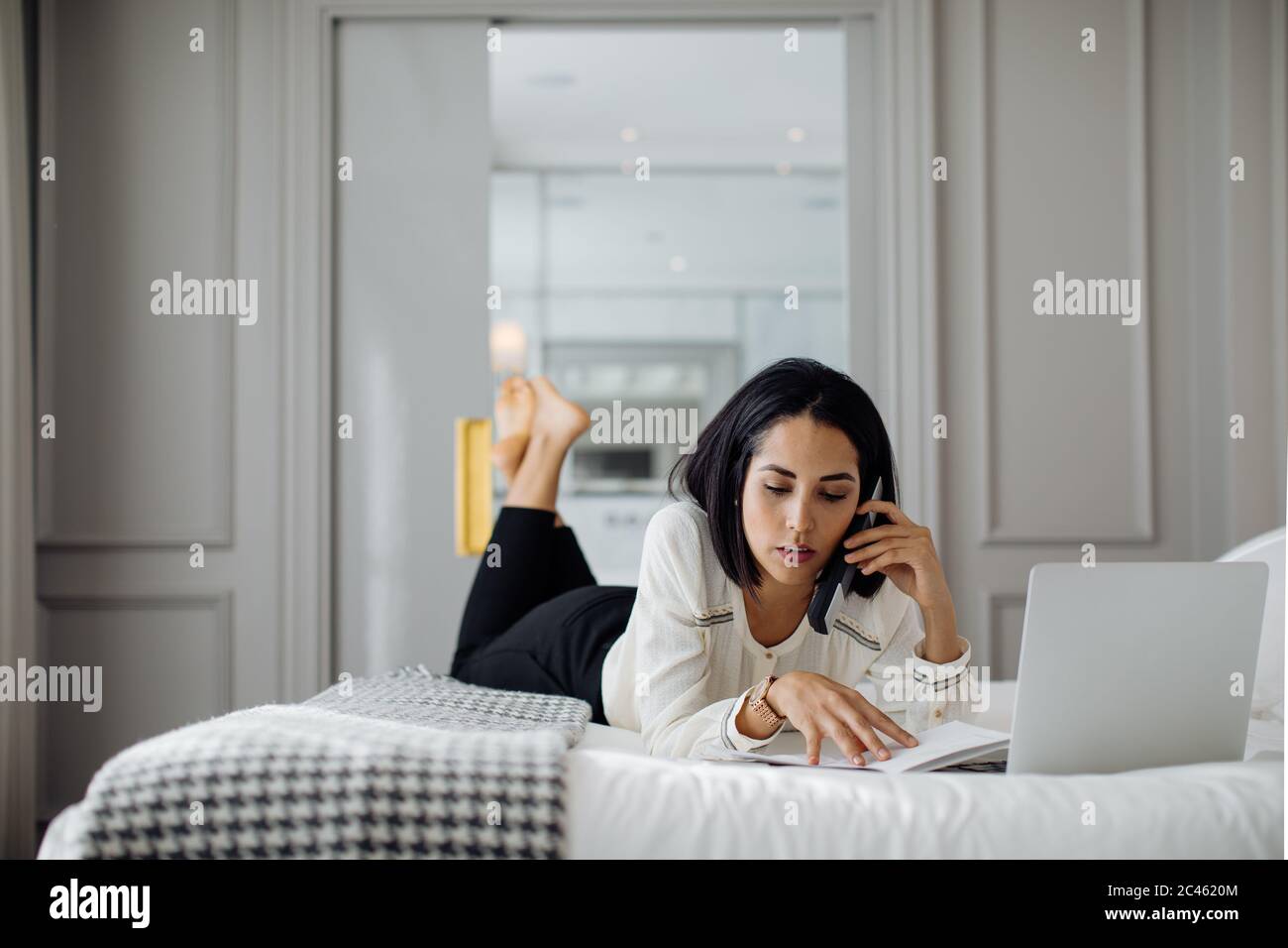 Businesswoman using smartphone and laptop in suite Stock Photo