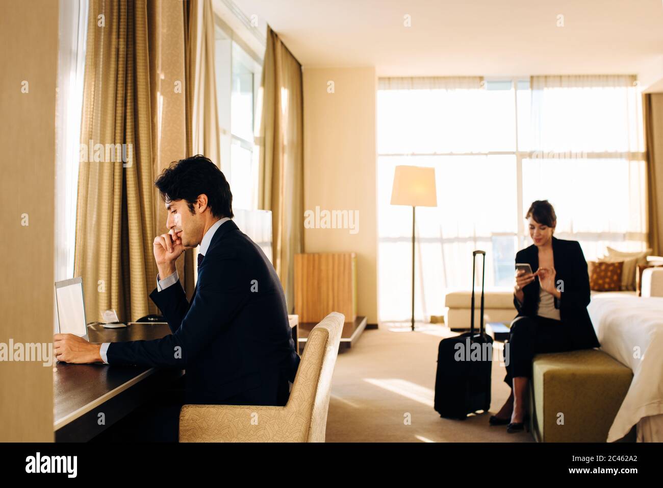 Businessman and businesswoman working in hotel bedroom Stock Photo