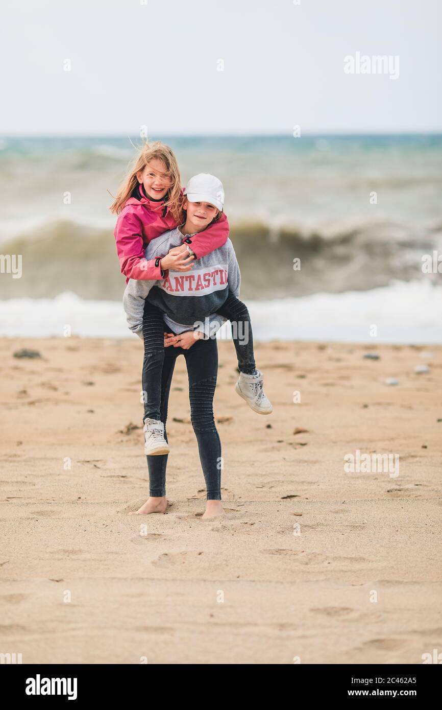 Two young girls enjoying beach holiday despite bad weather Stock Photo
