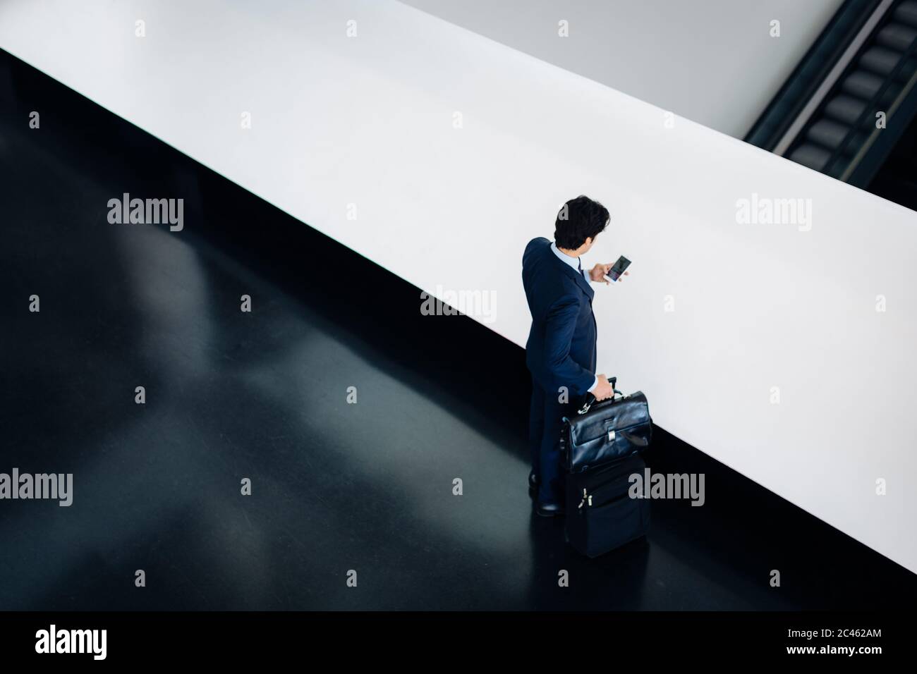 Businessman with wheeled luggage in hotel building Stock Photo