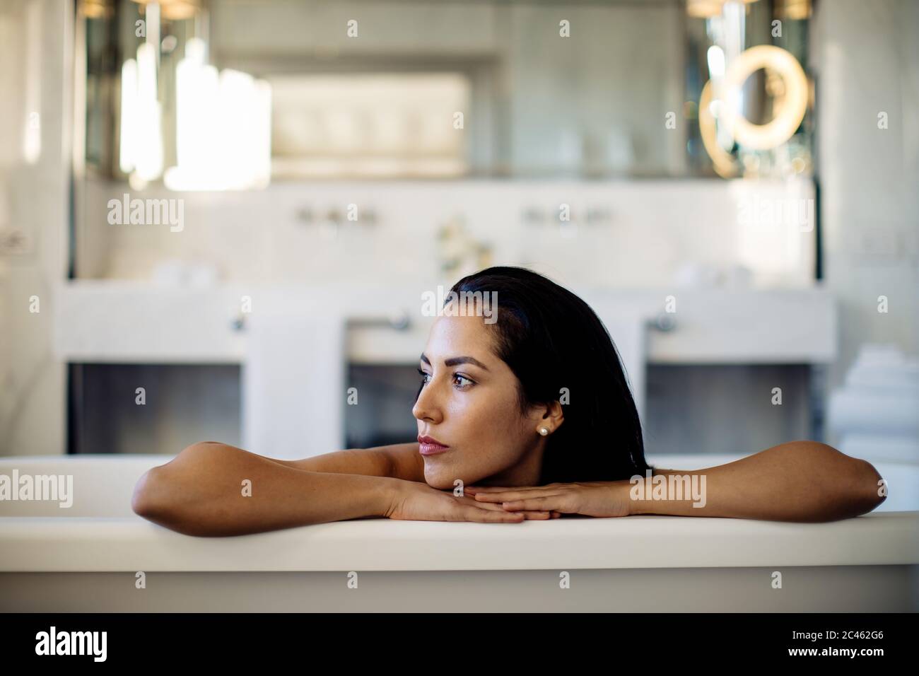 Woman relaxing in bathtub in suite Stock Photo