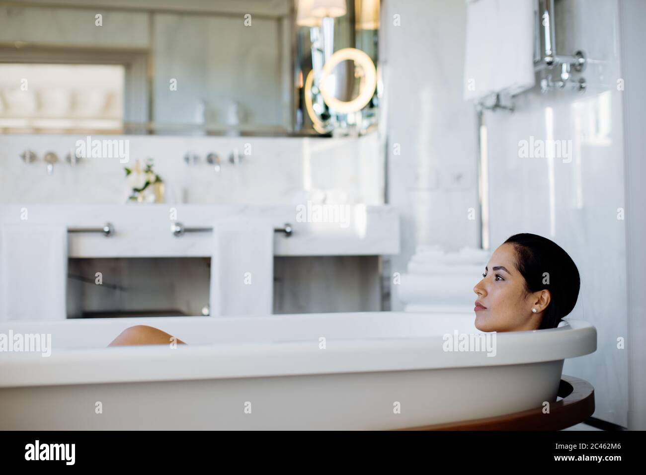 Woman relaxing in bathtub in suite Stock Photo