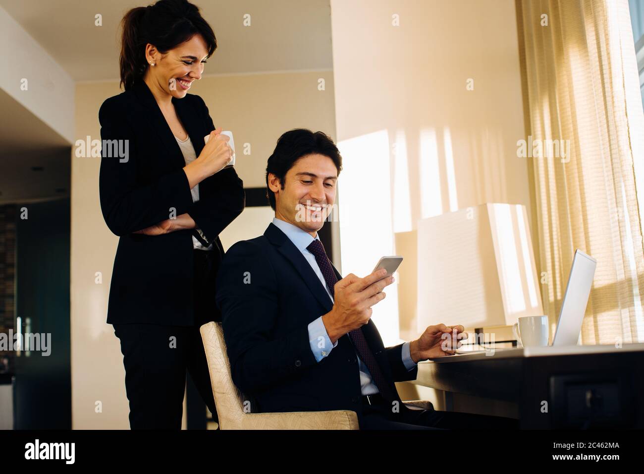 Businessman and businesswoman sharing text message in hotel room Stock Photo