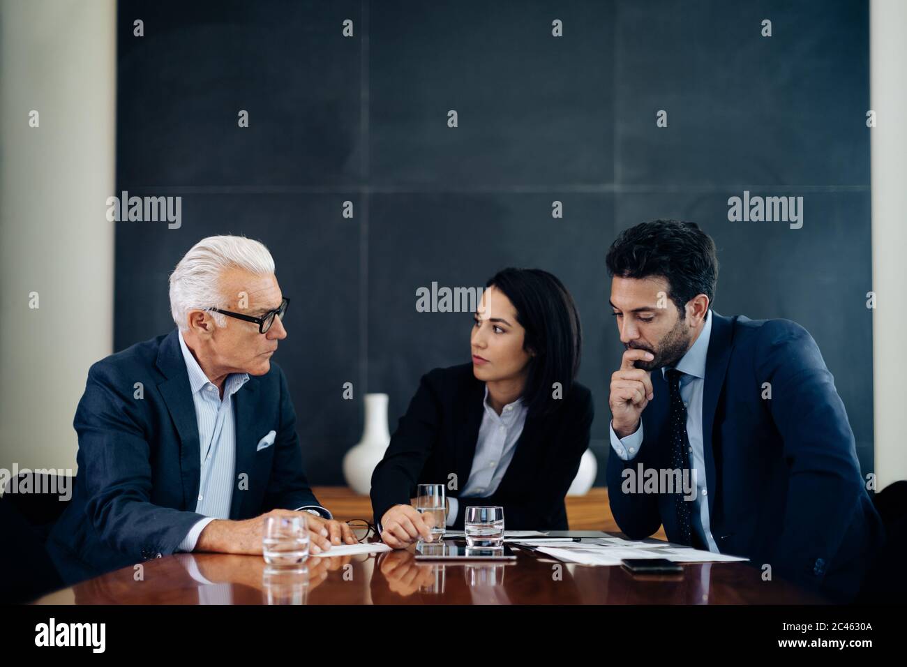 Businessmen and woman having discussion at boardroom table Stock Photo