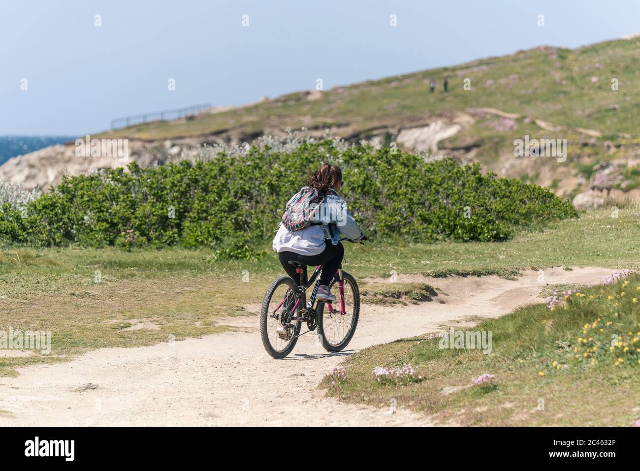 A female riding her mountain bike on a footpath on the coast in Newquay