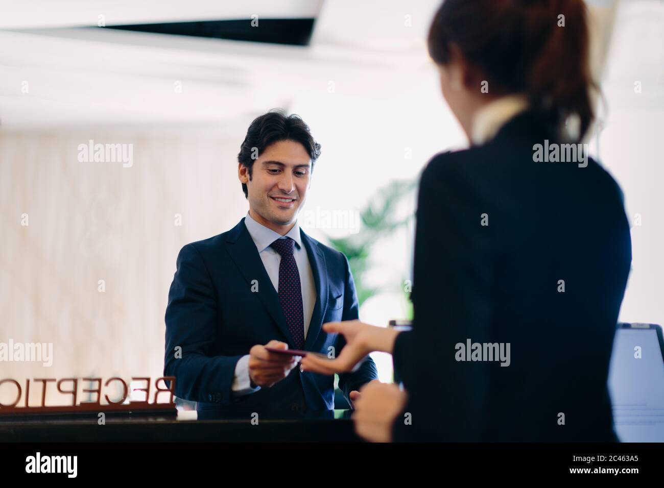 Businessman checking in at hotel reception Stock Photo - Alamy