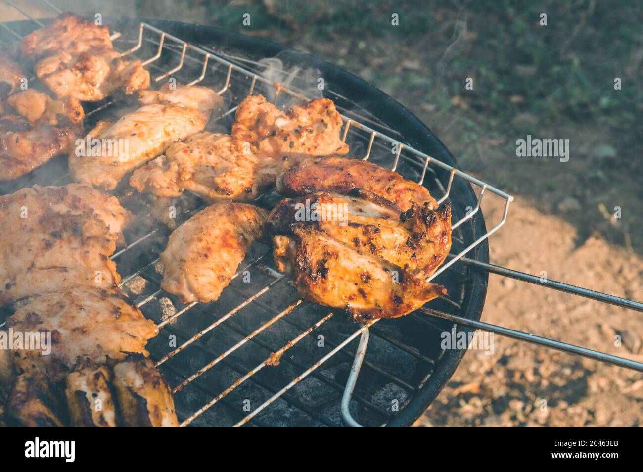 Close up of delicious and juicy chicken meat being cooked on a charcoal barbeque grill. Tasty snack party. Stock Photo