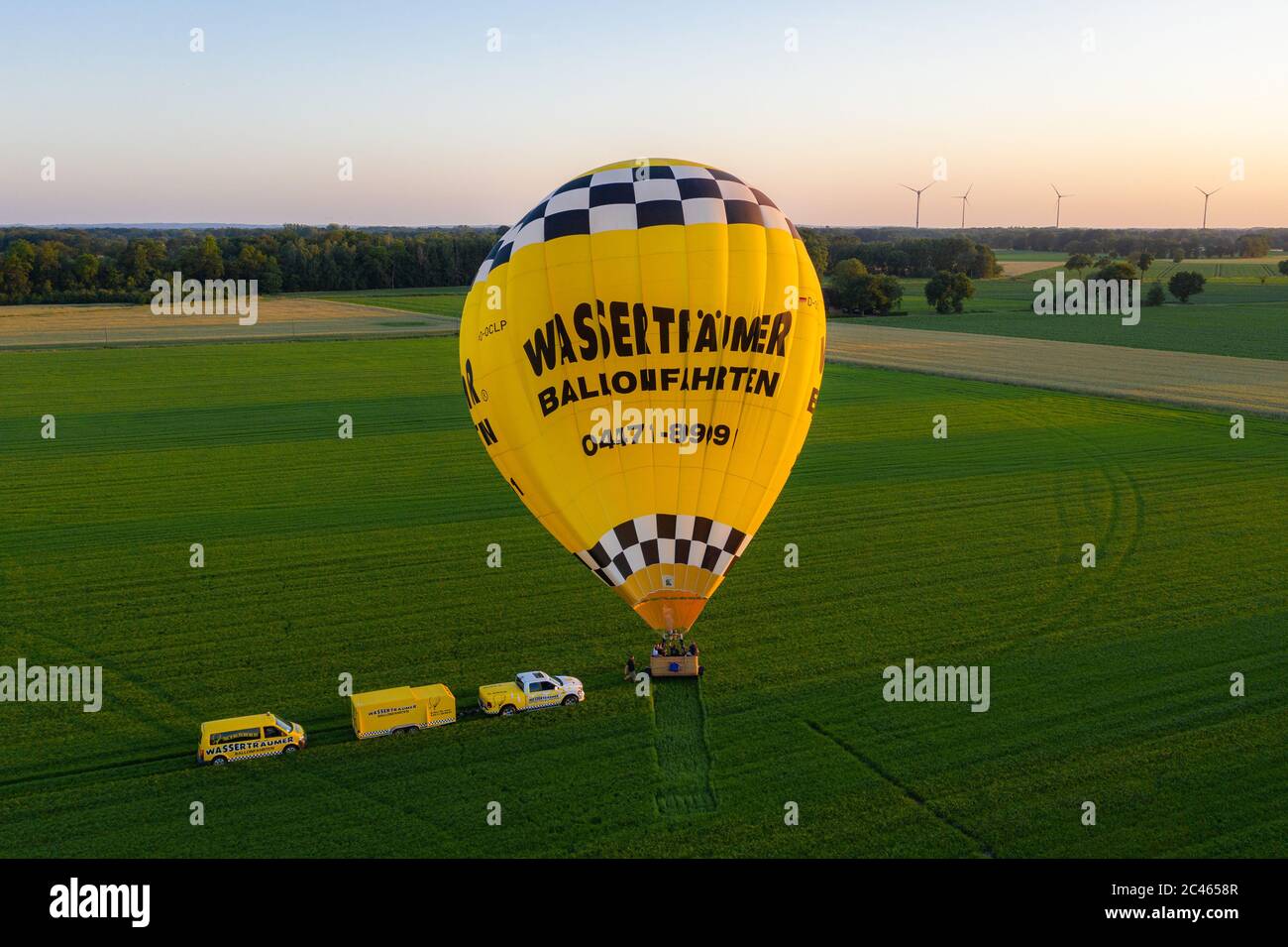Cloppenburg, Germany. 23rd June, 2020. The band 'Crackerjacks' lands with a hot-air balloon on a pasture after they have held a balloon concert over the town of Cloppenburg (recorded with a drone). Credit: Mohssen Assanimoghaddam/dpa/Alamy Live News Stock Photo