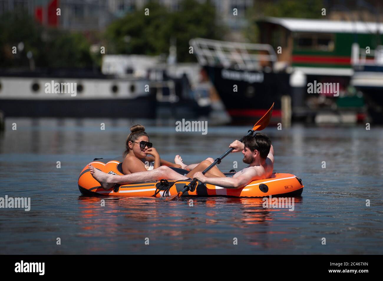 A couple sail in an inflatable dinghy in the London Docklands, in front