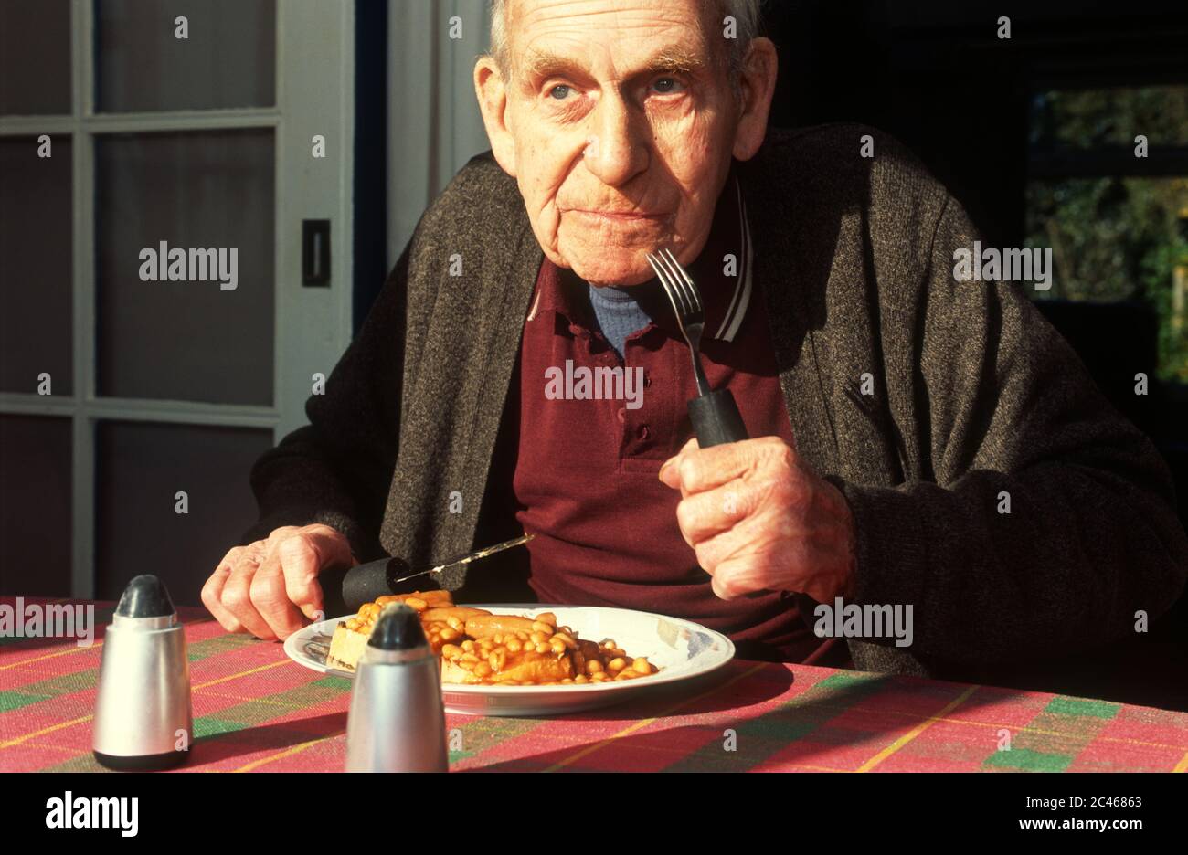 Old age pensioner eating baked beans and sausages for breakfast Stock Photo Alamy