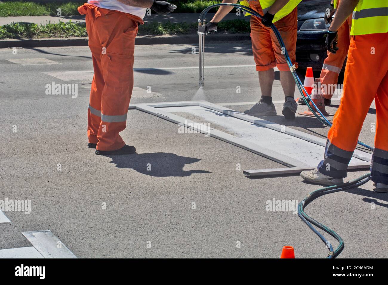 Workers are painting a stop line in a city street. Stock Photo