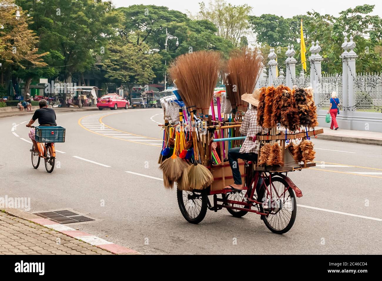 Street vendor of brooms and feather dusters travels a street in central Bangkok, Thailand, with the rickshaw full of goods Stock Photo