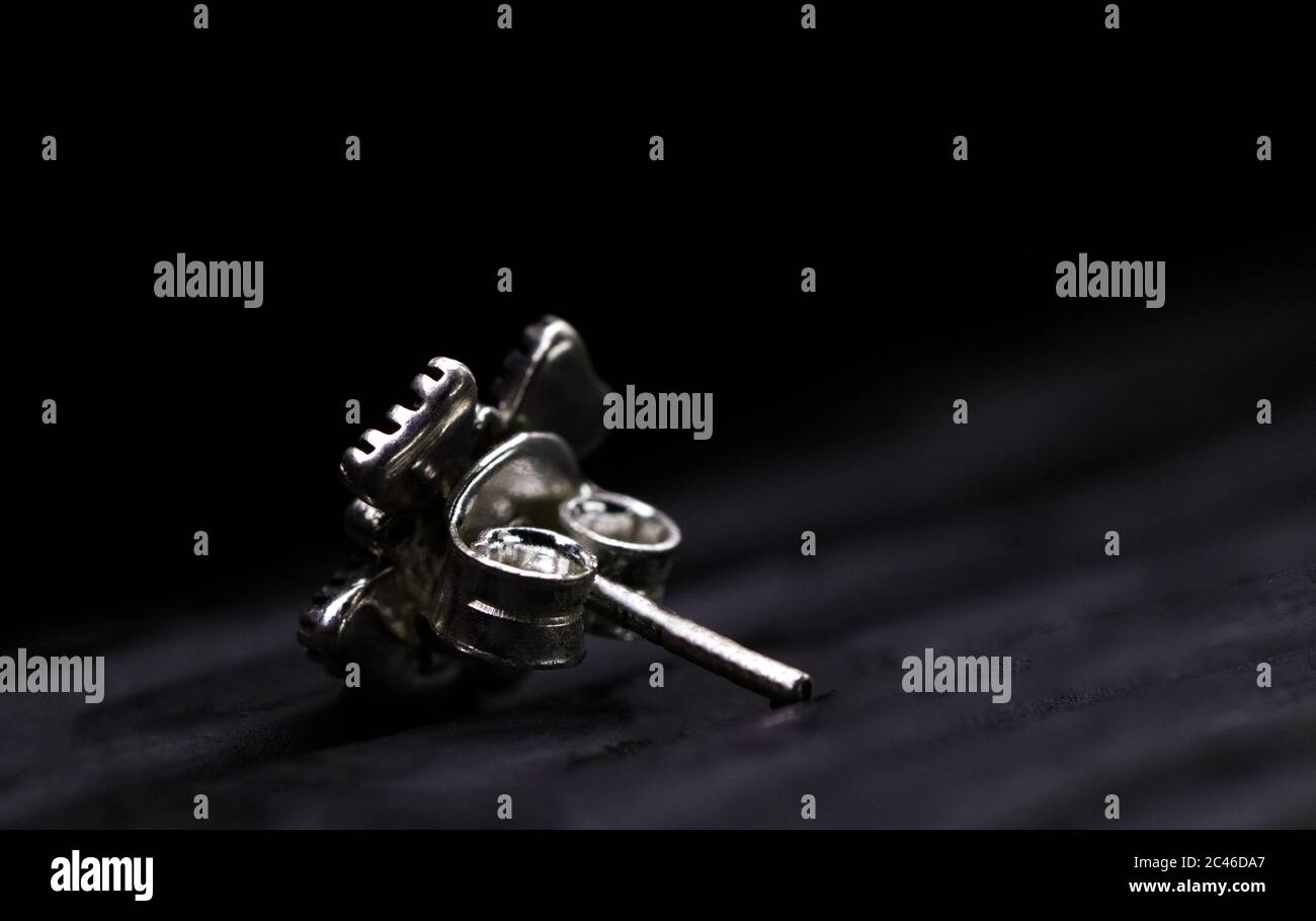 Closeup shot of a silver nail earring under the lights isolated on a black background Stock Photo