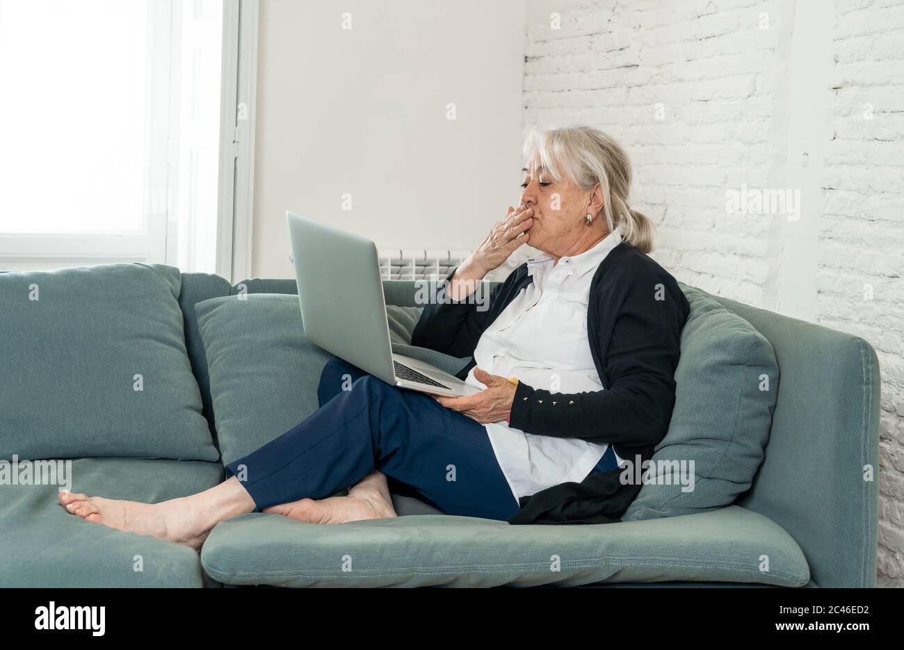 COVID-19 Stay connected. Happy senior woman at home video calling family on laptop or online chatting with long distance friends. Coronavirus lockdown Stock Photo