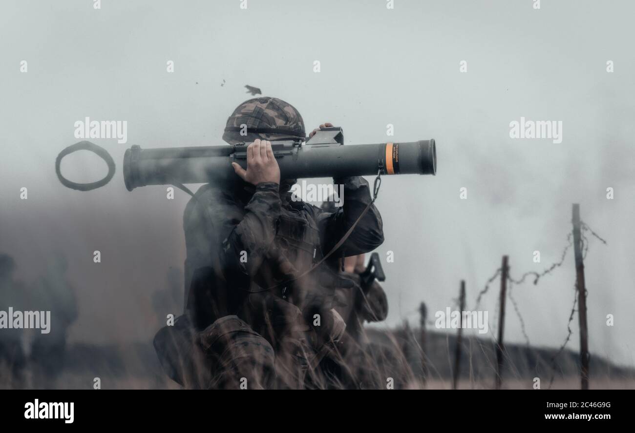 Closeup shot of a soldier in a field firing bazooka Stock Photo