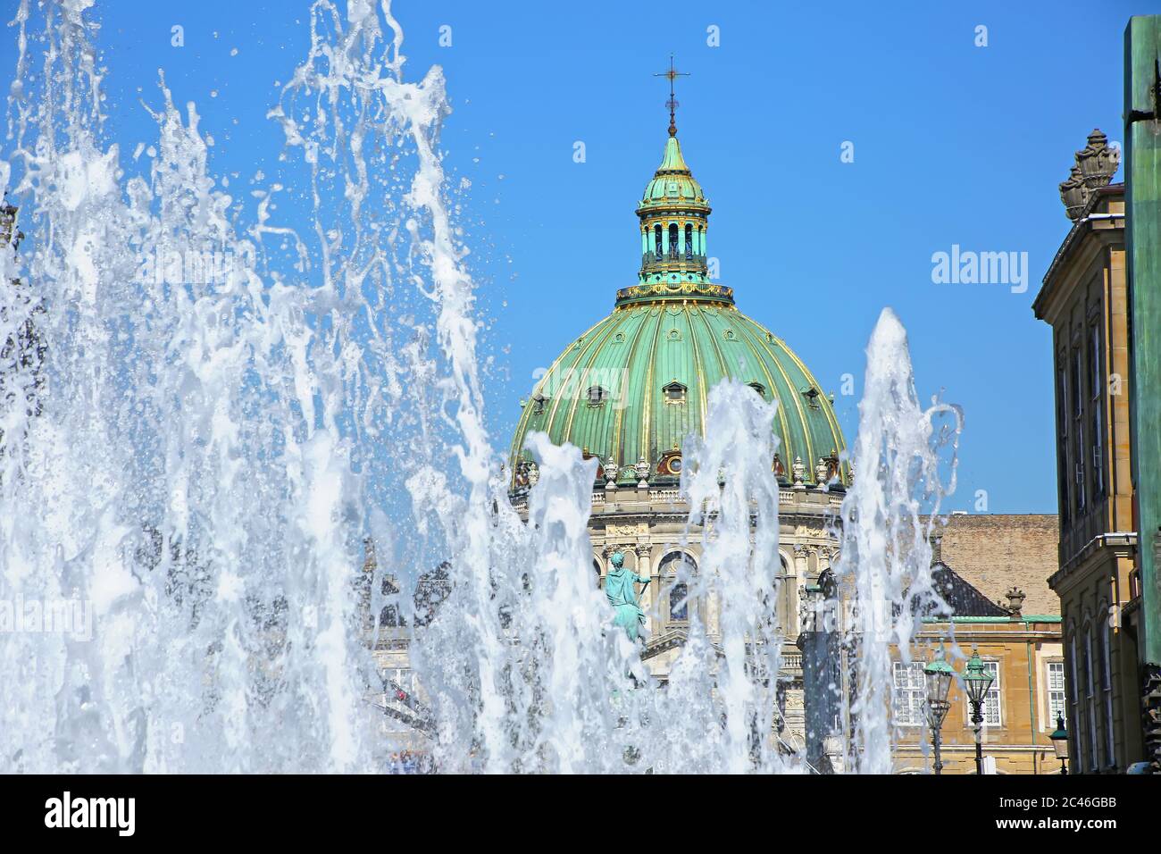 Fountain of water with Amalienborg Palace Square and a statue of Frederick V on a horse in the background, Copenhagen, Denmark. Stock Photo