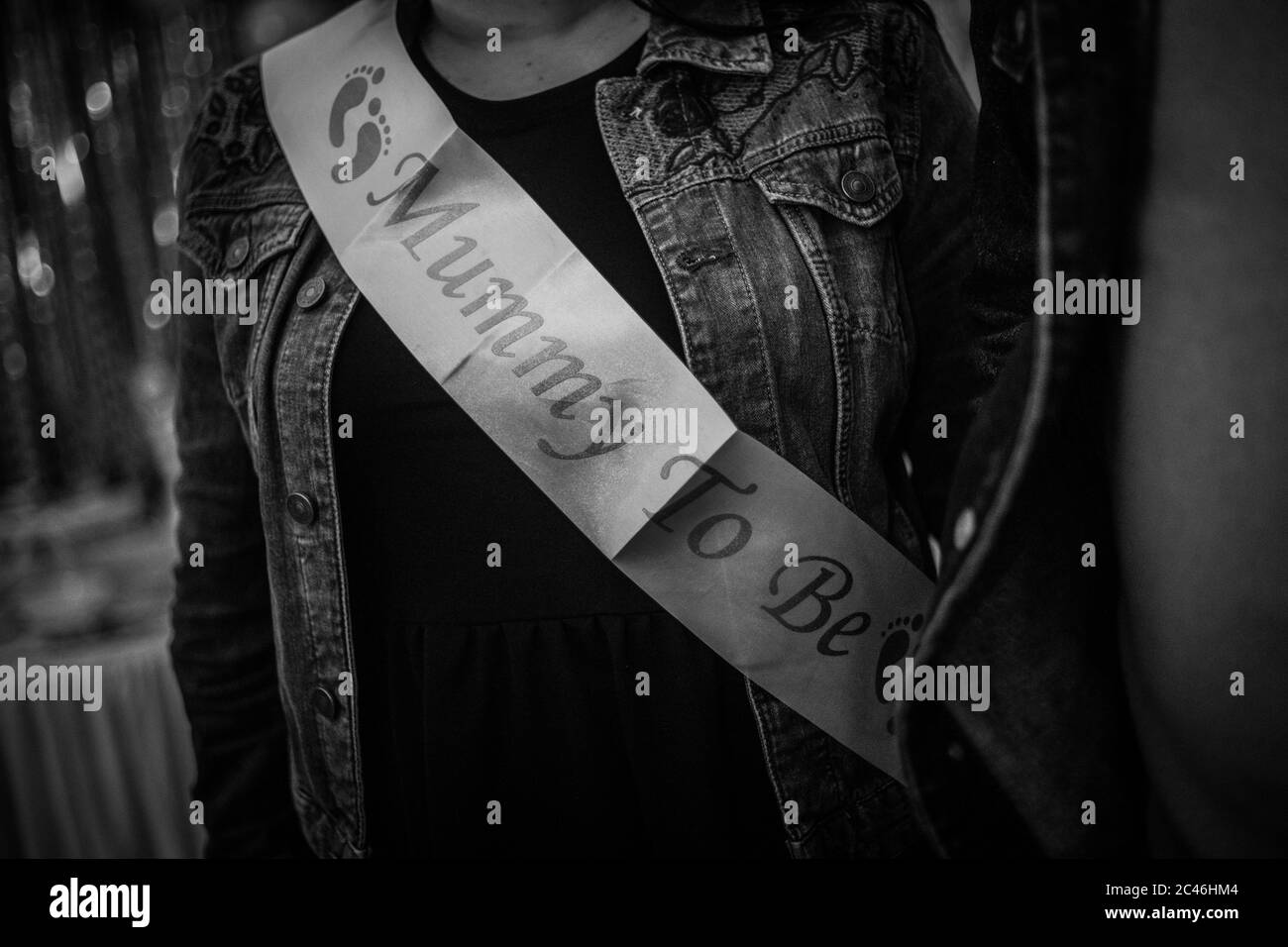 Grayscale closeup shot of a female with a ribbon with Mummy to be text Stock Photo