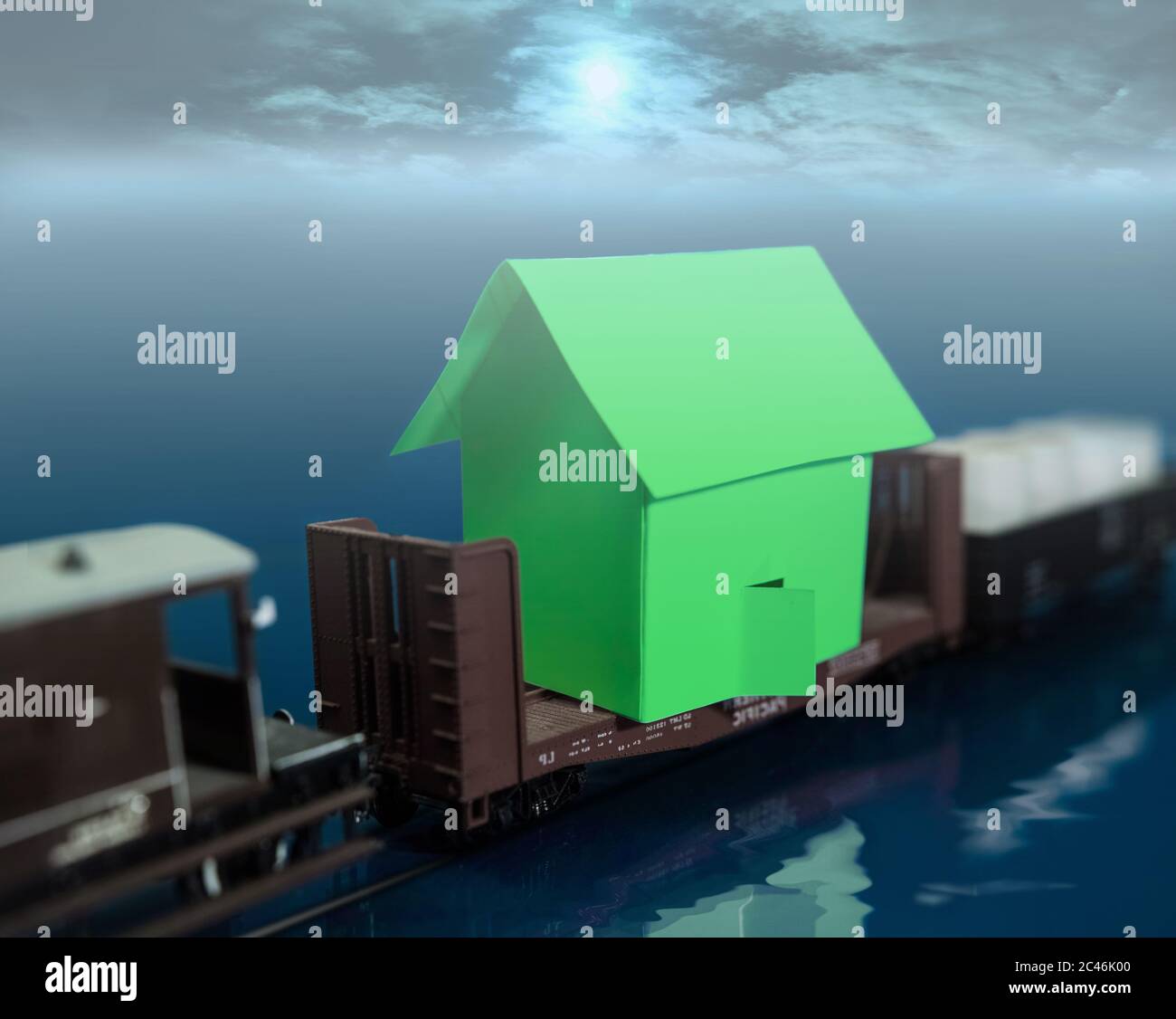 The surreal vision of a freight train crossing the sea, while carrying a house on one of its platforms.. Stock Photo