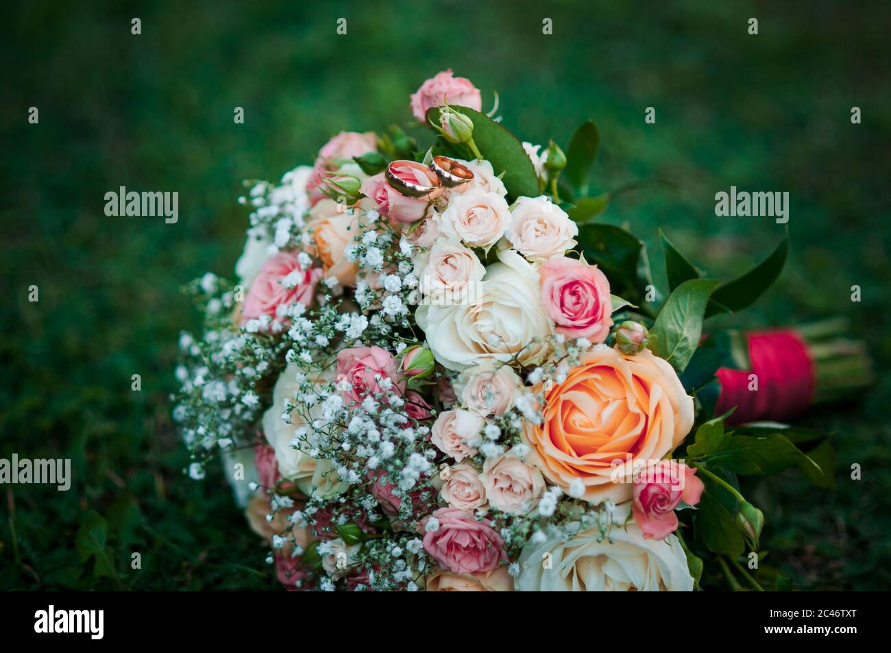 Flower composition, wedding bouquet with ribbon, boutonniere and two golden rings Stock Photo