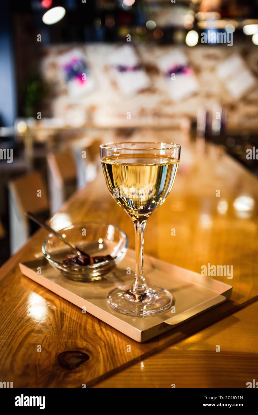 A photo of a light yellow transparent cocktail in a nick and nora glass, served on a small tray with garnish in a small glass bowl Stock Photo