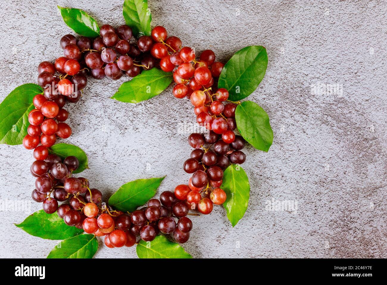 Pattern from red grapes and leaves on gray background. Stock Photo