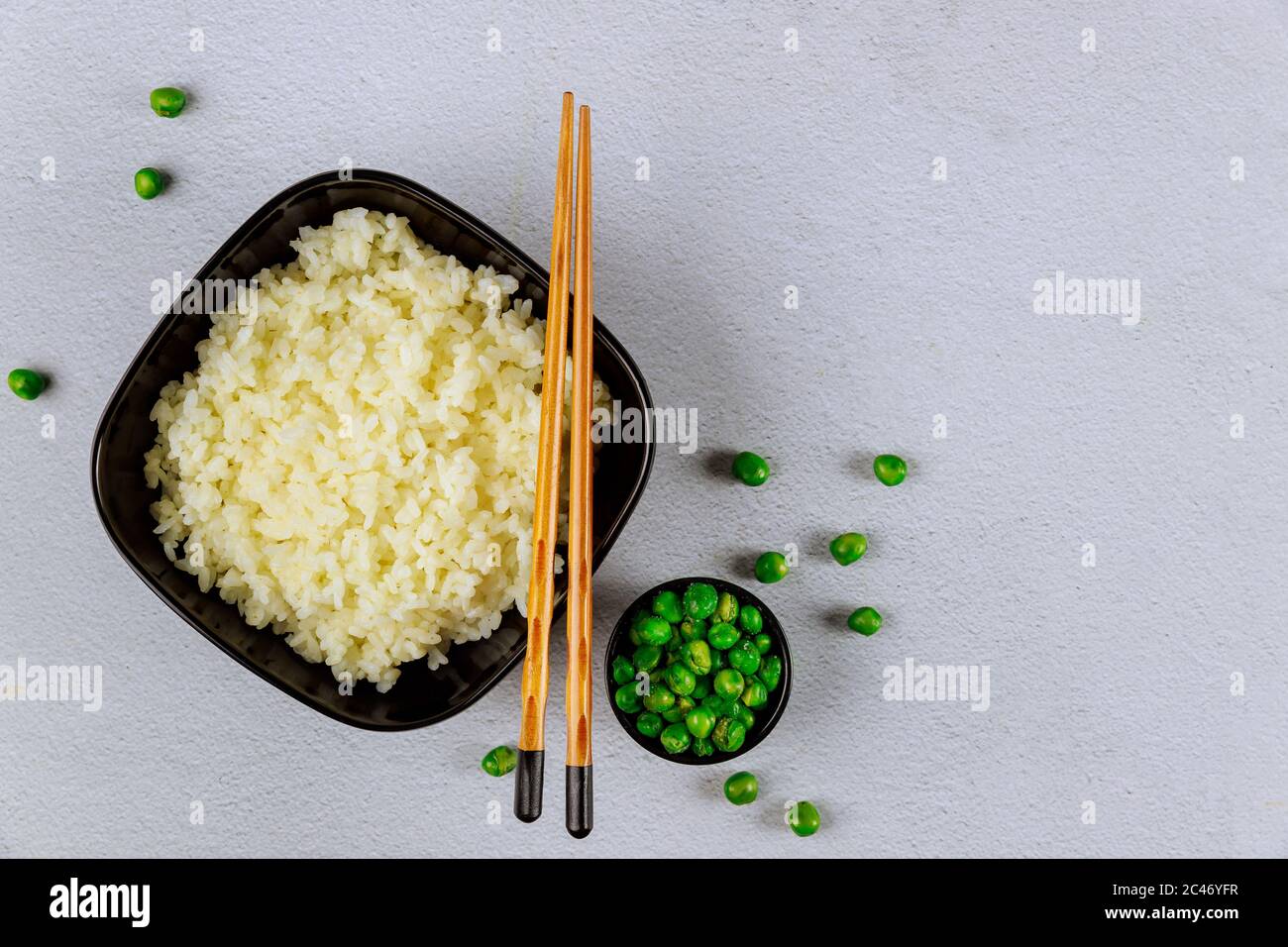 Cooked plain rice in black bowl with chopsticks on white background. Stock Photo