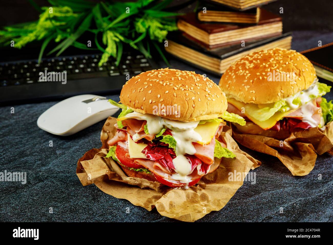 Sandwich Computer Mouse Two big sandwiches on dark desk with keyboard, mouse and books. Work ...