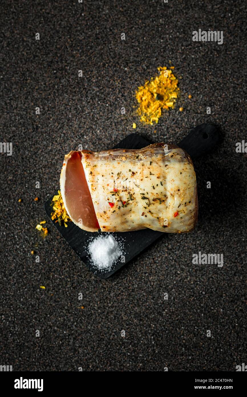 Dry-cured meat with spices and salt on dark grey background Stock Photo