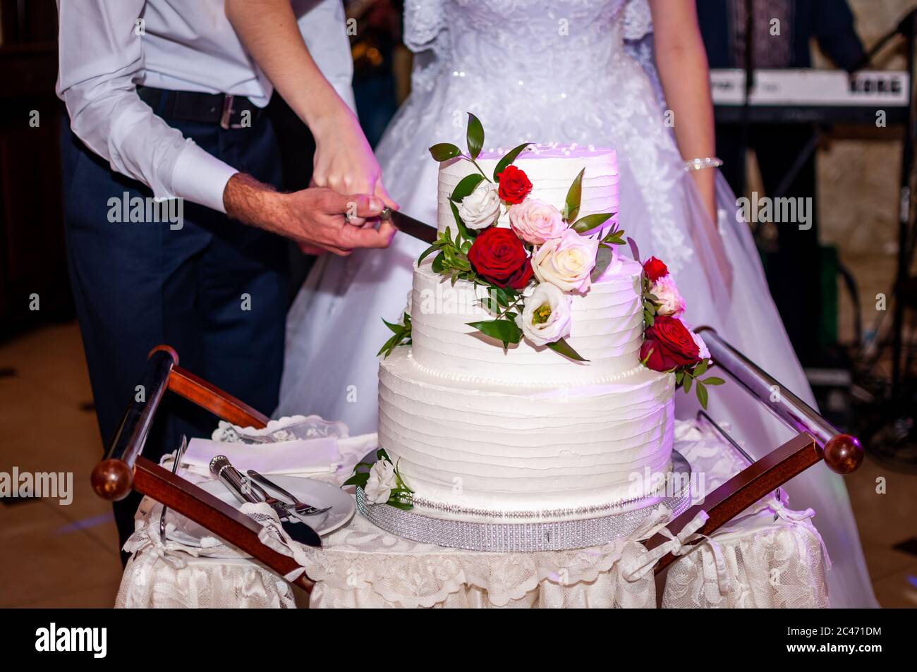 Bride and groom cuting white wedding cake Stock Photo
