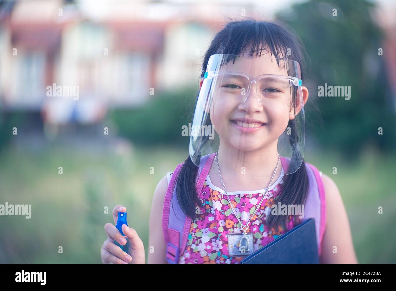 Little child girl student wearing face shield during she going back to school after covid-19 quarantine. Stock Photo