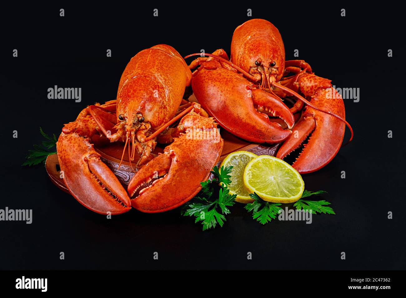 Boiled red lobsters with lemon on black background. Stock Photo