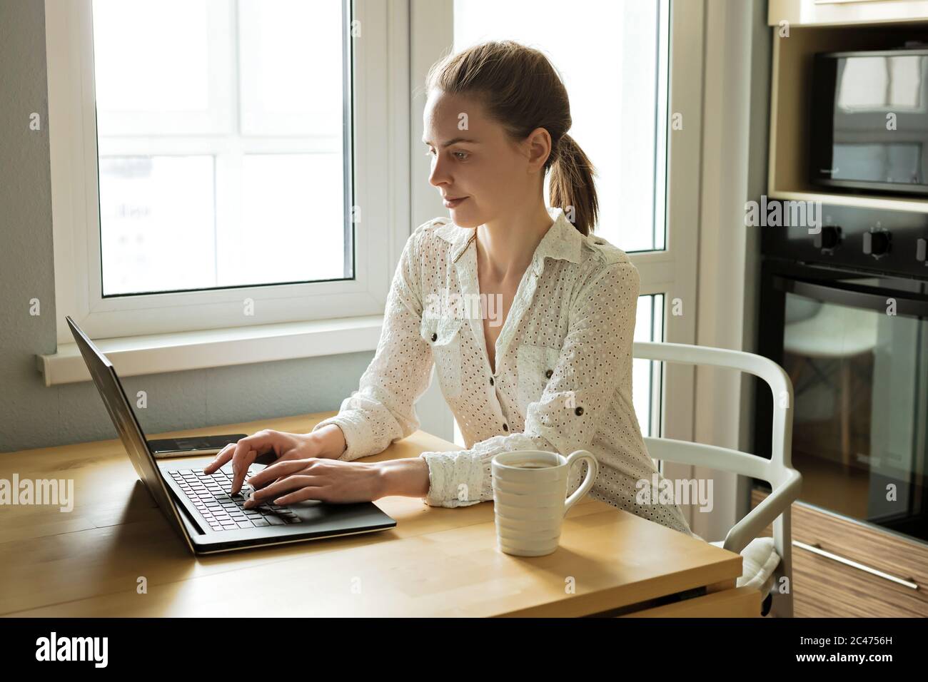 Attractive young caucasian business woman working with computer laptop on wooden table at home. Freelance, work from home Stock Photo