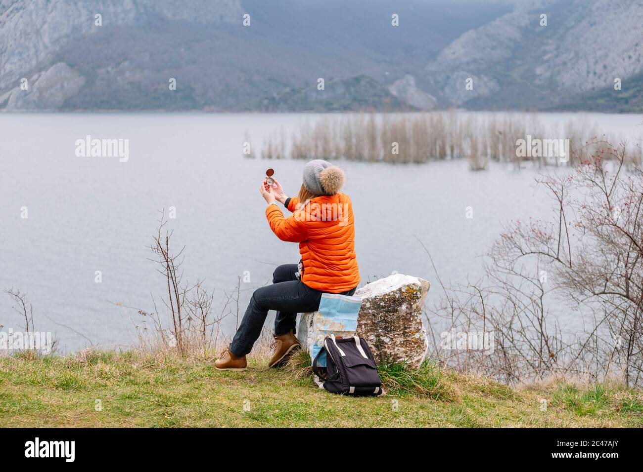 A tourist woman in hat and coat with a compass in nature Stock Photo