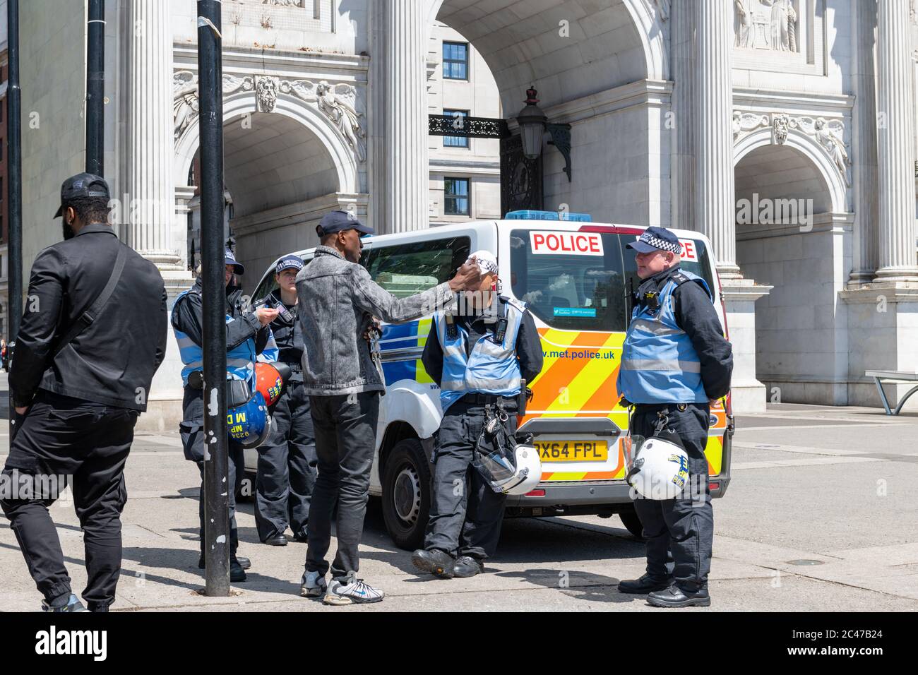 An organisor of a demonstration in Hyde Park discussing the event with police liasion officers in the square by Marble Arch. London. Stock Photo