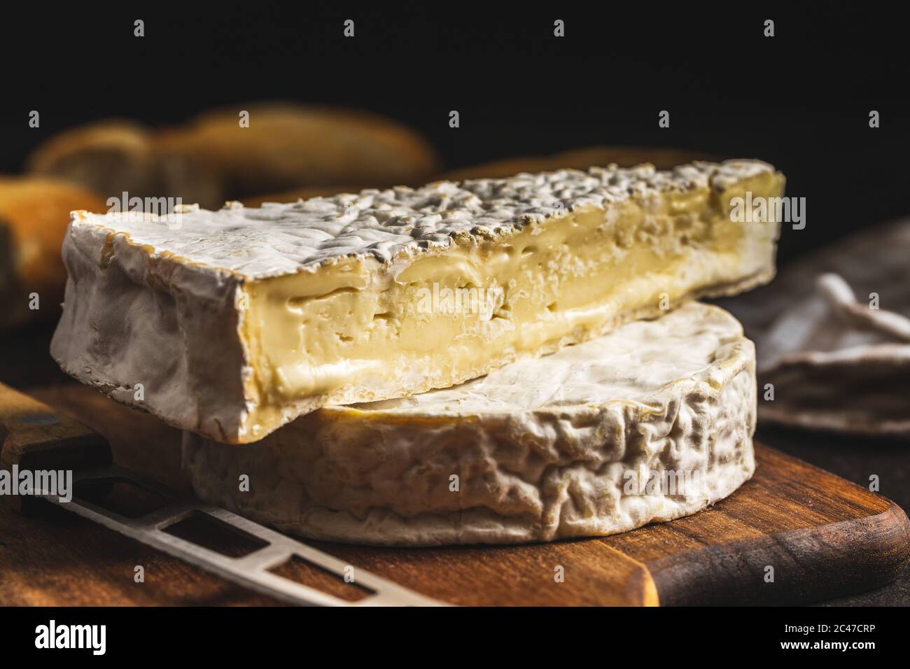 Brie cheese. White soft cheese with white mold on cutting board. Stock Photo