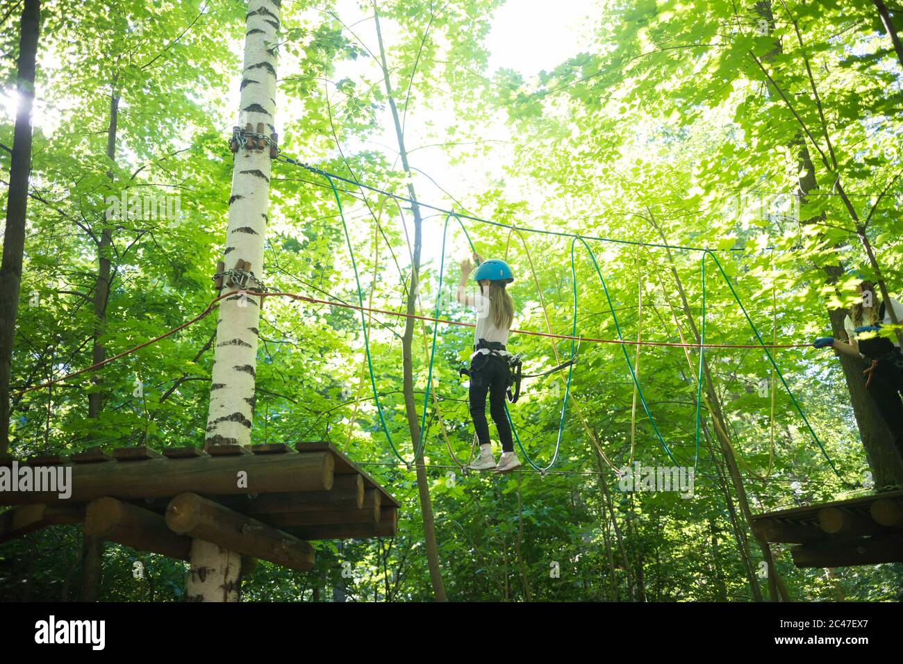 Rope adventure - a little girl walking on a rope bridge. Mid shot Stock ...