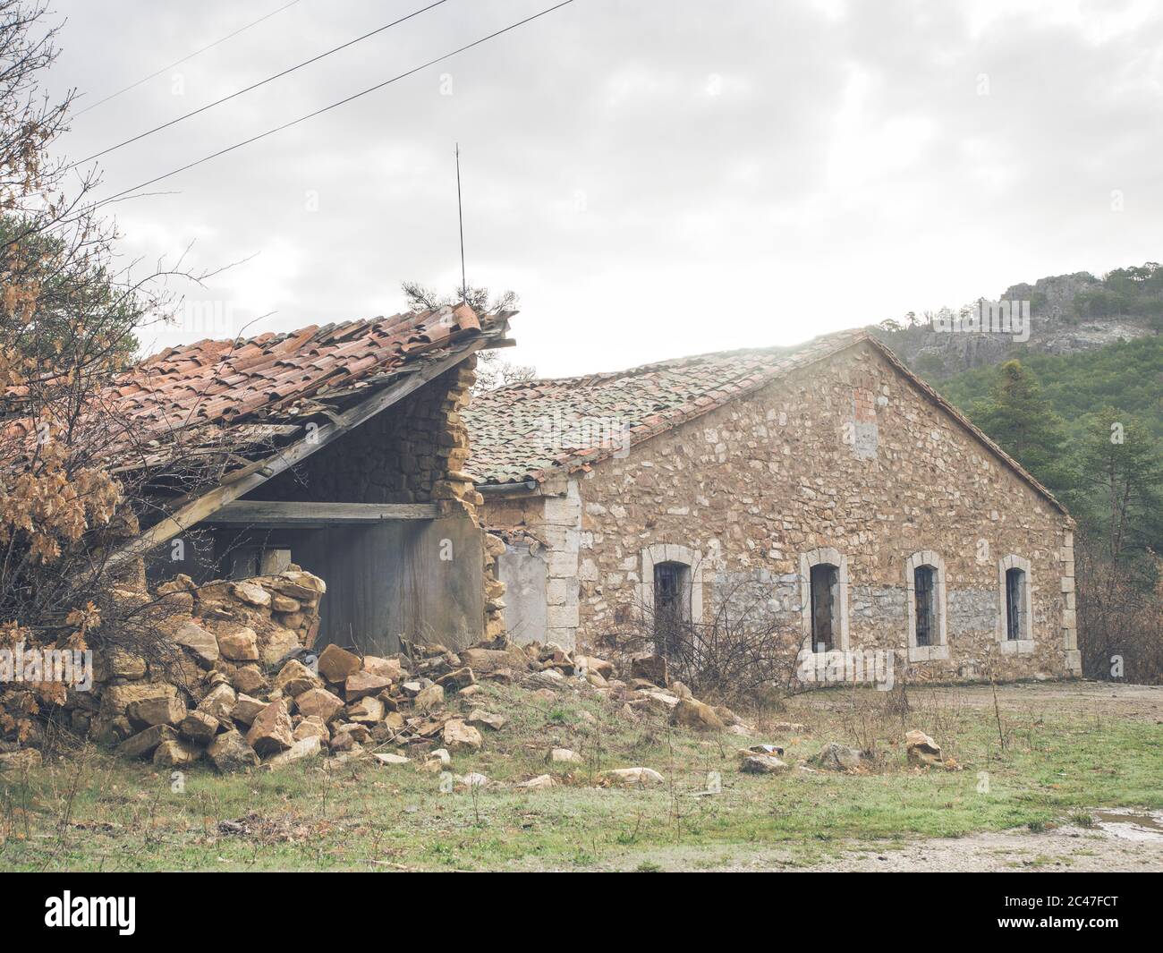 Old destroyed building surrounded by mountains under a cloudy sky Stock ...