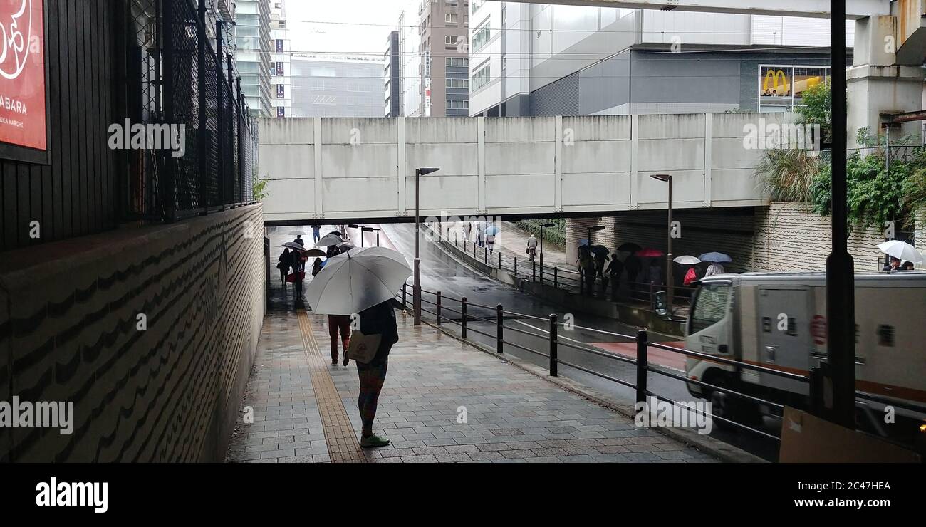 Girl under a umbrella walking down the street in Tokyo Japan Stock Photo