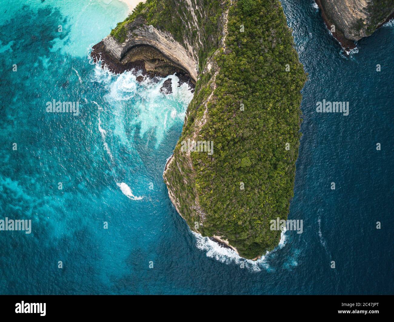 Aerial shot of the cliffs covered in greenery surrounded by the sea ...