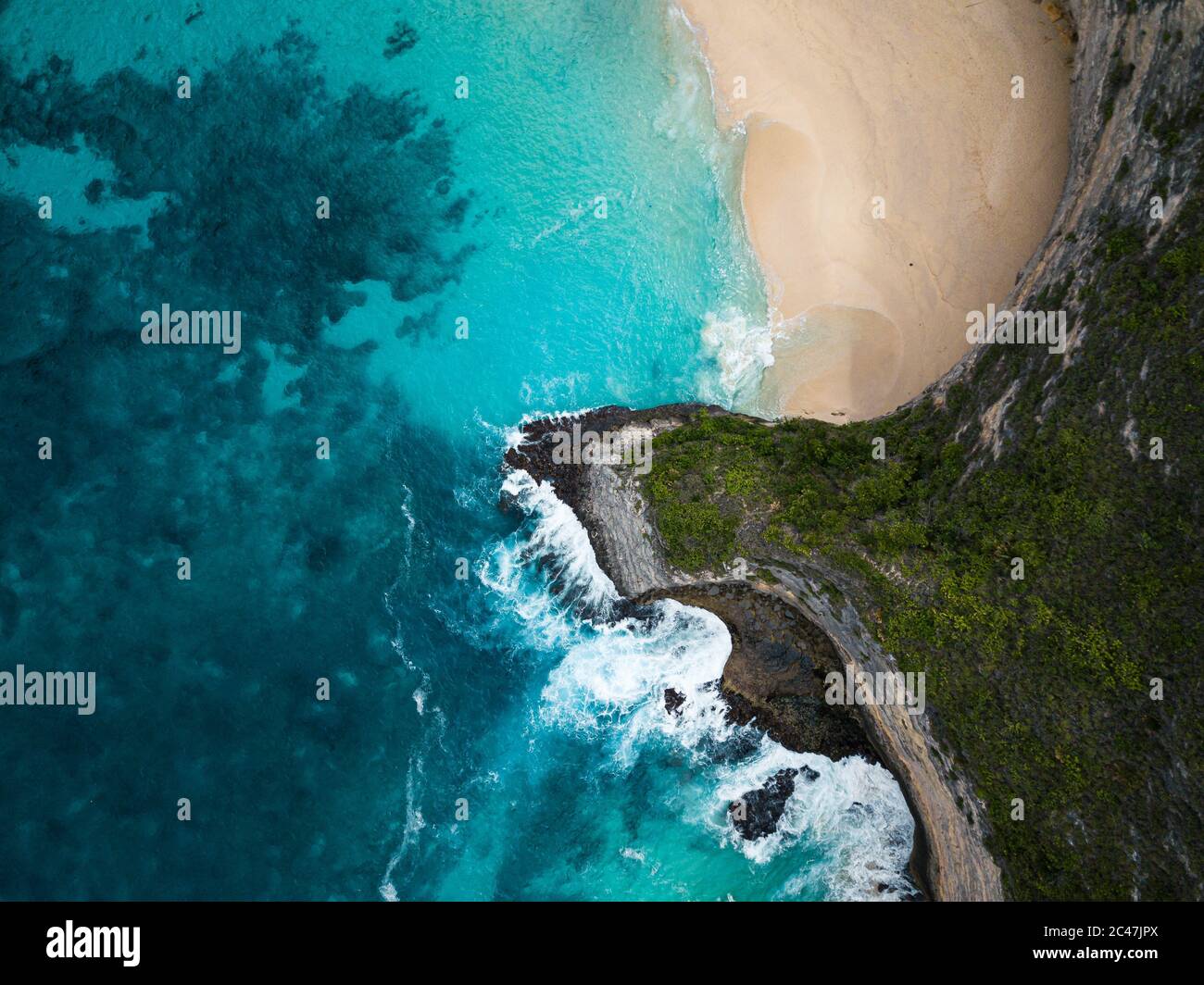 Aerial shot of the cliffs covered in greenery surrounded by the sea ...